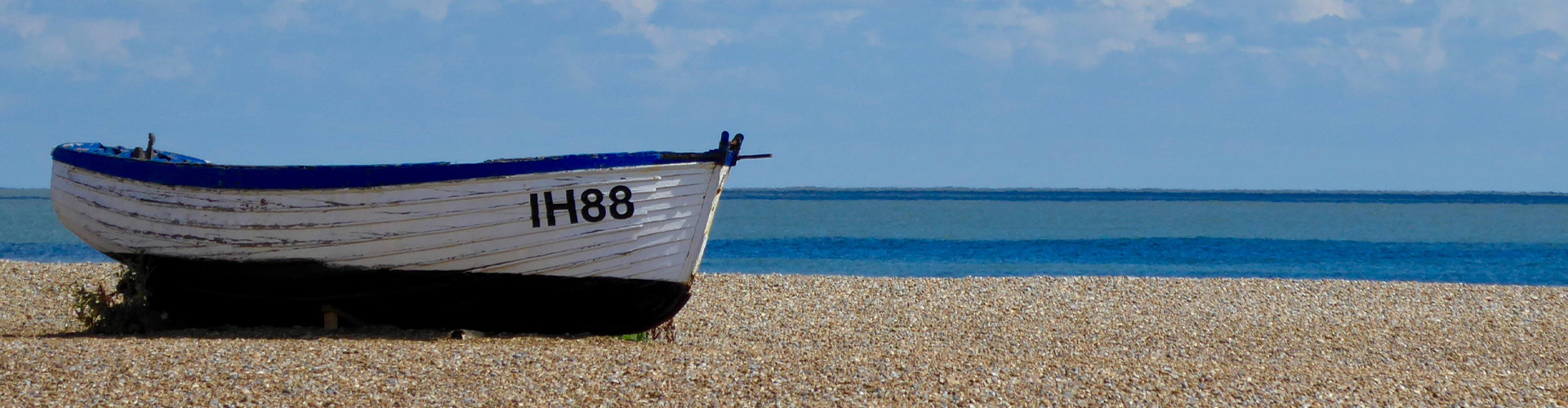 Blue and white boat on a stoney beach.