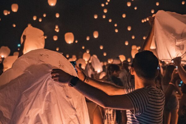 Paper lanterns being lit and floating into the sky.