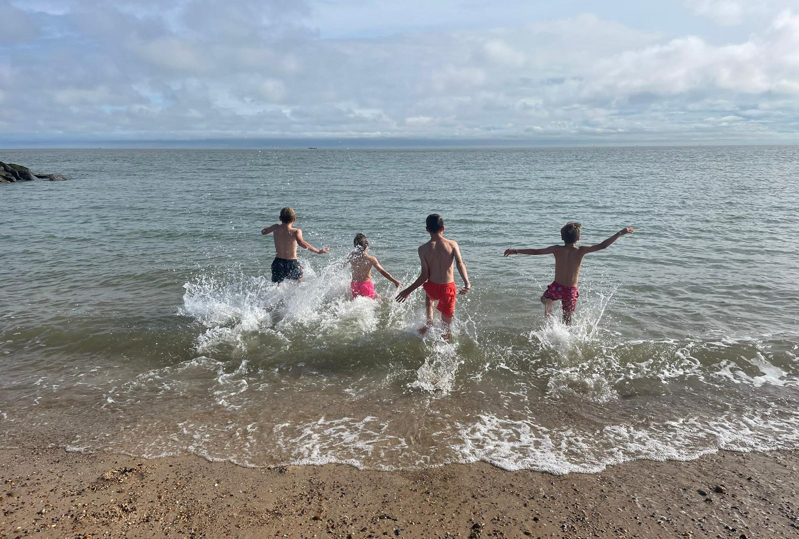 BOys running into the sea at Felixstowe beach Cooky's & Cream hut